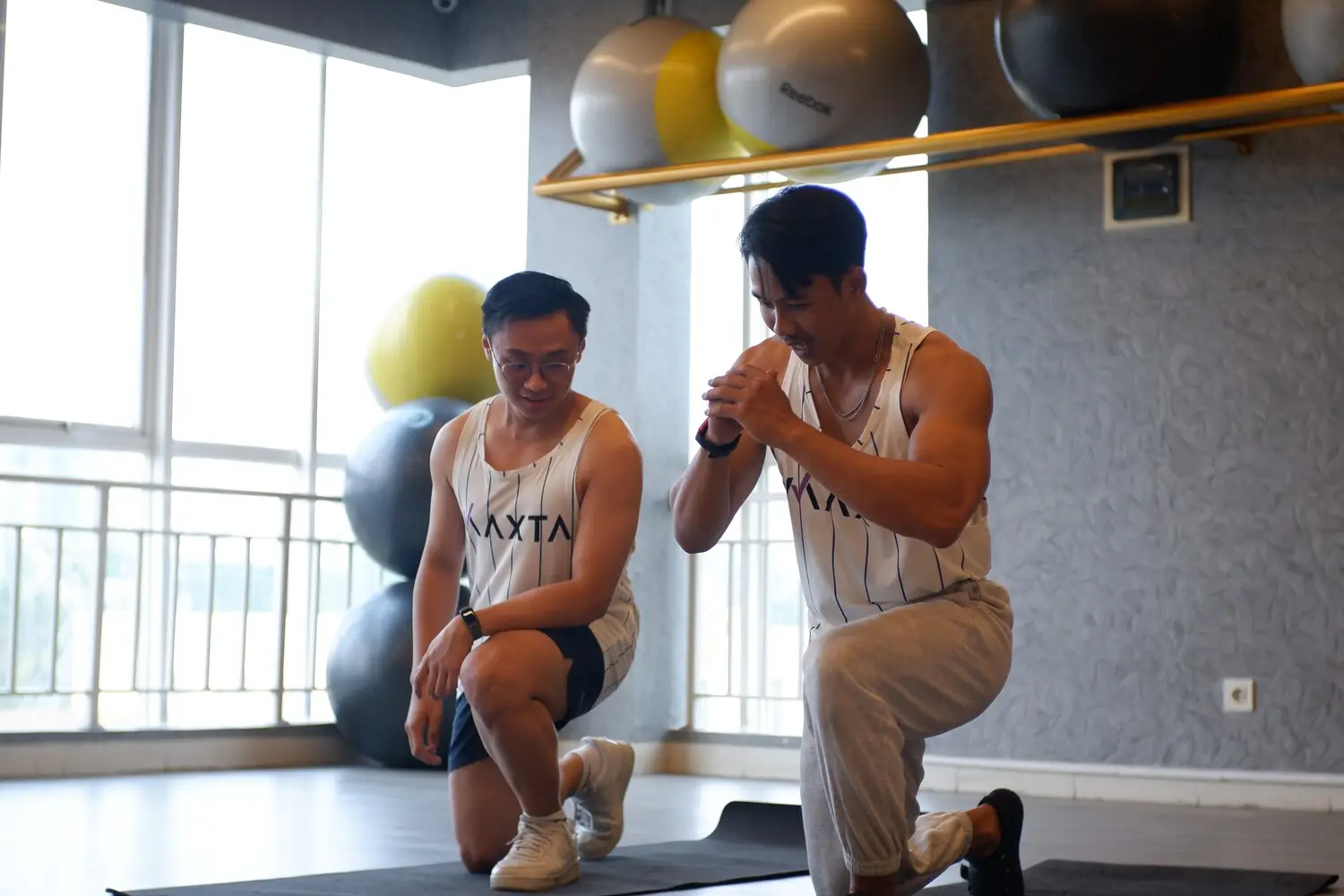 dua orang tim maxta sedang melakukan gerakan pemanasan bersama di tempat gym
