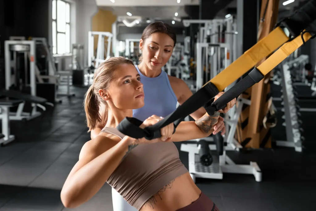 seorang perempuan menggunakan TRX untuk latihan di gym