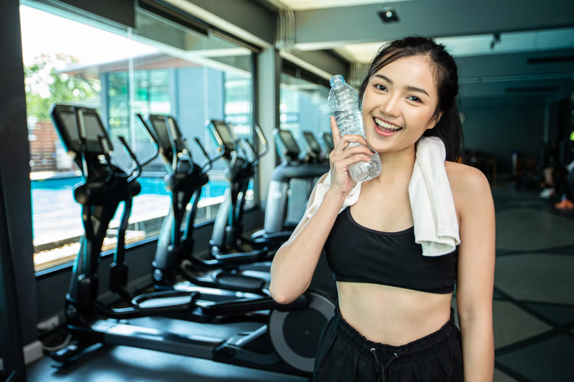 seorang wanita berada di gym sambil memegang botol minum